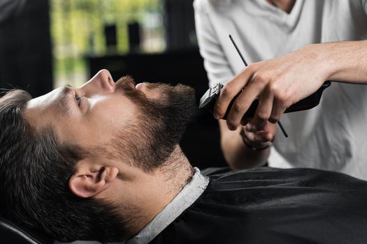 Trimming the beard with a shaving machine. Advertising for barbershop and men's beauty salon.