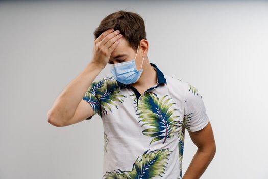 Headache man in blue medical mask isolated white background. Man touches her head because sicks coronavirus covid-19. Pandemic 2020.