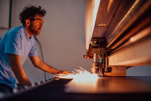 Within heavy industry. A man works in a modern factory on a CNC machine. Selective focus. High-quality photo