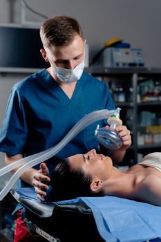 Anesthesiologist making ingalation anesthesia for patient. Doctor puts a mask on the patient before starting operation.