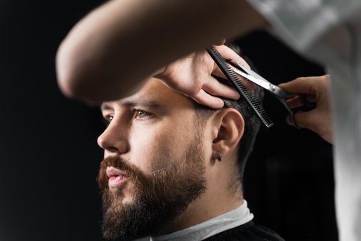 Barber making hairstyle for confident bearded hipster. Advertising for barbershop and men's beauty salon