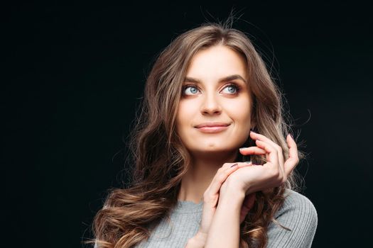 Portrait of happy fashion female with nice hairstyle and beautiful blue eyes posing at studio. Cheerful girl looking away and smiling. Isolated on dark background