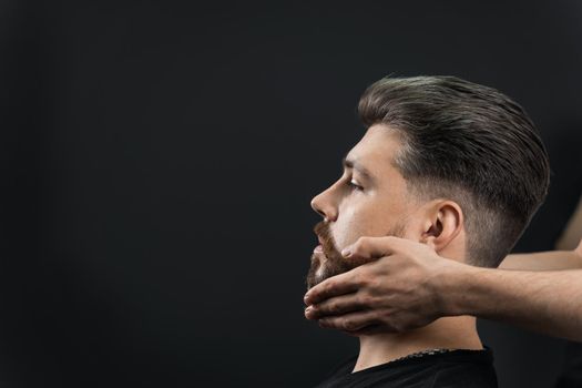 Fixing the shape of the beard with wax. The result of a haircut in a barbershop