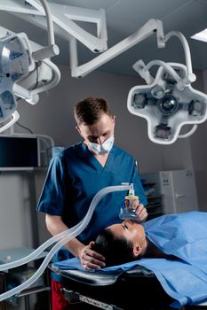 Anesthesiologist making ingalation anesthesia for patient. Doctor puts a mask on the patient before starting operation.
