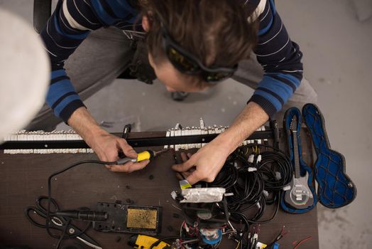 Industrial worker man soldering cables of manufacturing equipment in a factory. Selective focus. High quality photo