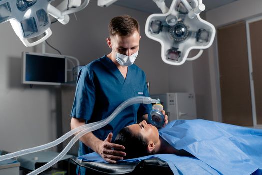 Anesthesiologist making ingalation anesthesia for patient. Doctor puts a mask on the patient before starting operation.