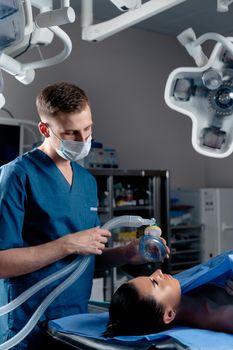 The doctor puts on a mask for artificial ventilation of the lungs in the intensive care unit.