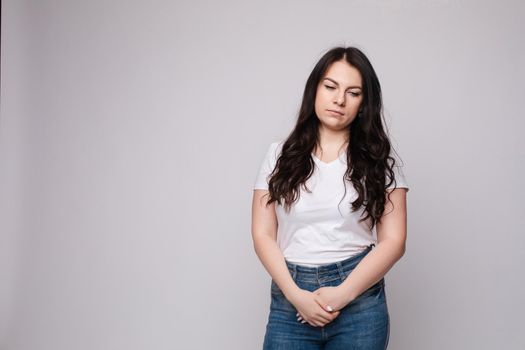 Upset young beautiful woman standing with crossed hands isolated at white studio background medium long shot. Unhappy European female looking down having negative emotion