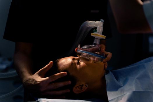 The doctor puts on a mask for artificial ventilation of the lungs in the intensive care unit.