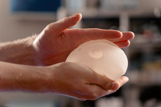 Silicone implant in hand close-up. Breast augmentation and lift surgery.