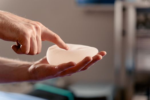 Silicone implant in hand close-up. Breast augmentation and lift surgery.