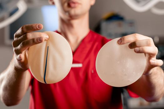 The surgeon shows different types of silicone implants. Breast augmentation surgery