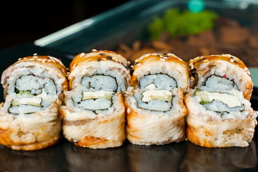 Rolls with eel, avocado, cucumber, cream cheese, nori, white and black sesame seeds close-up. Traditional Japanese cuisine.