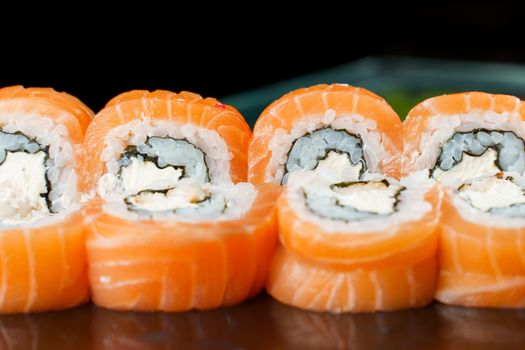 Philadelphia rolls with salmon, cream cheese, cucumber, avocado, nori close-up. Traditional Japanese cuisine.