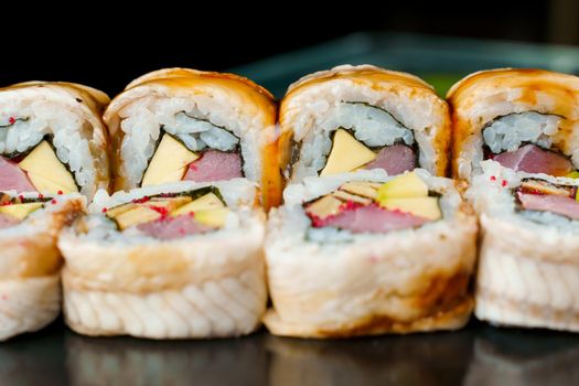 Unagi rolls with tuna, tobiko caviar, cheddar cheese, nori, unagi sauce close-up. Traditional Japanese food
