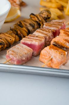 Barbecue seafood kebab with grilled mussels, tuna, salmon on a wooden skewer with white sauce and lemon