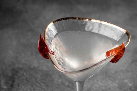 Cocktail in glass with chili on gray background. Devil alcohol drink