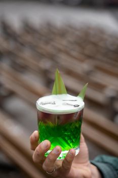 Green layered cocktail decorated with bamboo leaves on a gray background