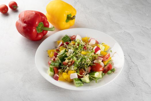 Wheat germ salad, tomatoes, peppers, radish, cucumber, olive oil. Vegetable salad on white plate on gray background