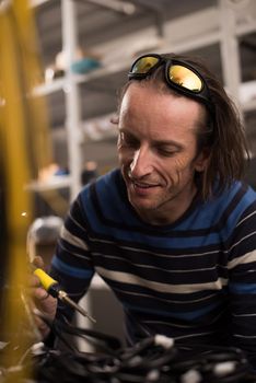 Industrial worker man soldering cables of manufacturing equipment in a factory. Selective focus. High quality photo