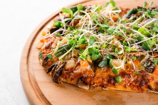 Pinsa romana with salami, cheese, mushrooms, decorated with microgreens on wooden boardon white background