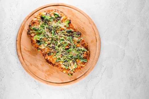 Pinsa romana with salami, cheese, mushrooms, decorated with microgreens on wooden boardon white background