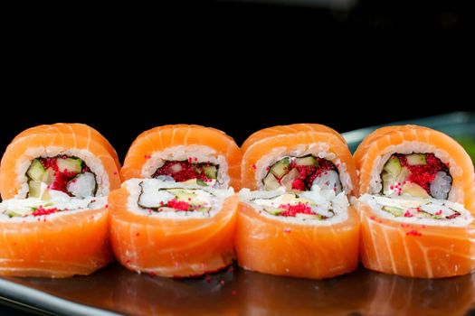 Rolls with salmon, tobiko caviar, avocado, cucumber, nori close-up. Traditional Japanese cuisine