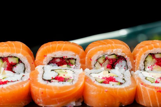 Rolls with salmon, tobiko caviar, avocado, cucumber, nori close-up. Traditional Japanese cuisine