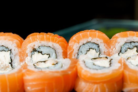 Philadelphia rolls with salmon, cream cheese, cucumber, avocado, nori close-up. Traditional Japanese cuisine.