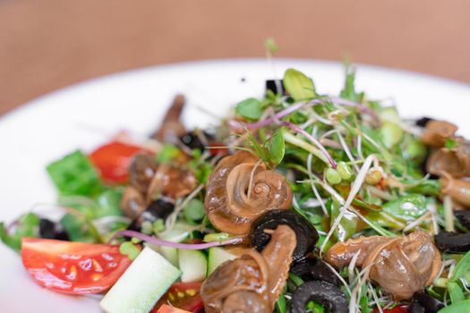 Salad with snail, olive, tomatoe cherie, cucumber and greens.