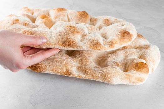 Touching and checking quality dough for pinsa romana on light background. Gourmet italian cuisine