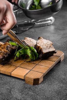 Grilled ribs slicing on a wooden plate on a gray background. Barbecue decoration