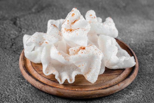 Rice paper chips fried in oil. Rice chips on a wooden board on gray background