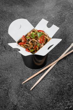 Wok in box spicy noodles in black food container. Fast food delivery service. Takeaway chinese street meal