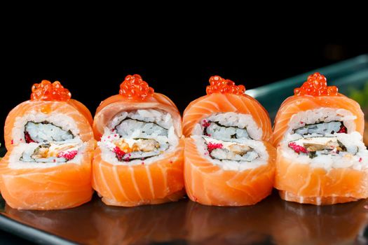 Roll red dragon with salmon, red caviar, tobiko, eel, rice, nori close-up. Sushi traditional Japanese cuisine.