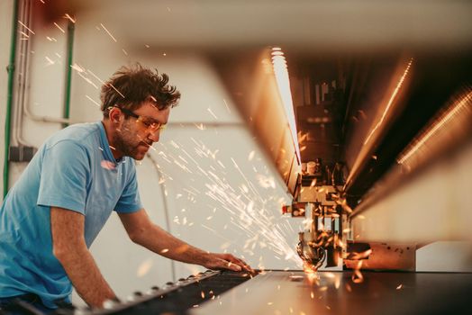 Within heavy industry. A man works in a modern factory on a CNC machine. Selective focus. High-quality photo