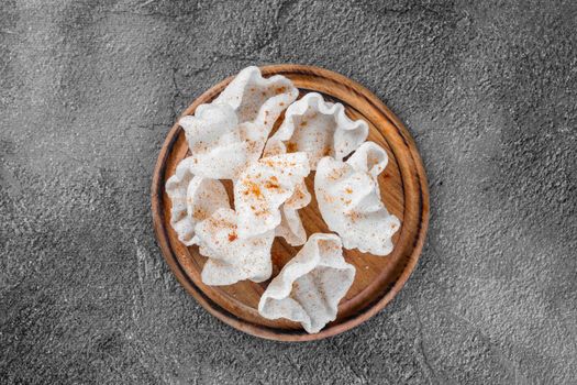 Rice chips on a wooden board on a gray background. Top view