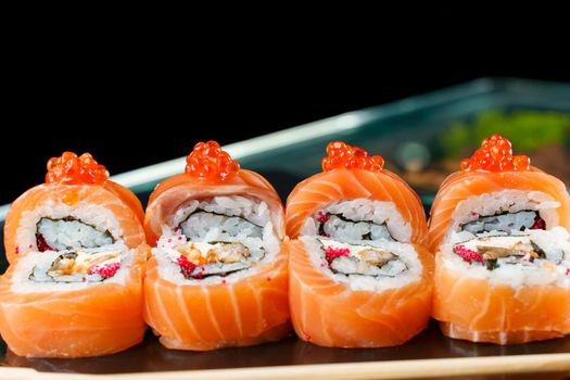 Roll red dragon with salmon, red caviar, tobiko, eel, rice, nori close-up. Sushi traditional Japanese cuisine