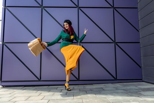 A happy shopaholic girl throws her bags near a shopping center. Have fun shopping on Black Friday. the girl in the store is happy with her purchases, throws packages. Consumer concept