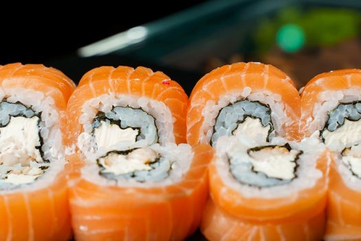 Philadelphia rolls with salmon, cream cheese, cucumber, avocado, nori close-up. Traditional Japanese cuisine.