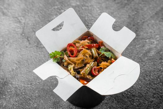 Wok in box rice noodles in black food container. Fast food delivery service. Takeaway chinese street meal