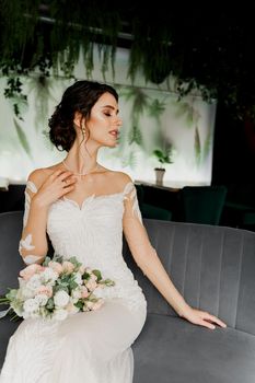 Bride in wedding dress and bridal veil seats on fashion chair in cafe. Advert for social networks for wedding agency and bridal salon.