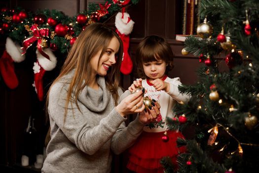 Mom and daughter decorate the christmas tree before the new year. Family traditions. Preparing for new year celebration