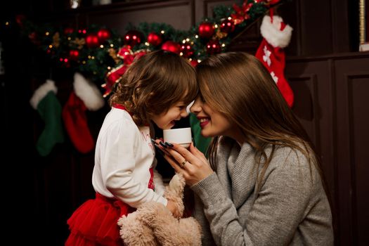 Mother and daughter preparing for christmas celebration. Having fun with family near new year tree. Pregnant woman with daughter