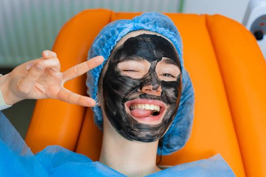 Black mask on girl face for carbon peeling. Dermatology and cosmetology. Using surgical laser