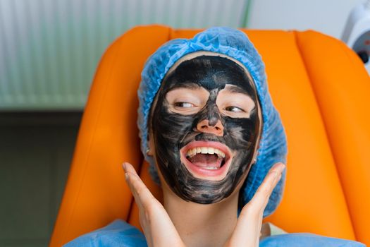 Black mask on girl face for carbon peeling. Dermatology and cosmetology. Using surgical laser