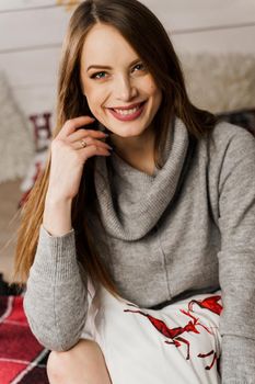 Young woman smiling in new year decoration. Christmas celebration. Attractive girl weared in warm woolen sweater and socks.
