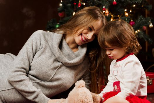 Mother and daughter preparing for christmas celebration. Having fun with family near new year tree. Pregnant woman with daughter