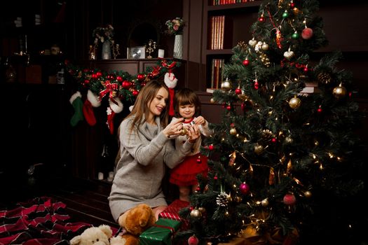 Mom and daughter decorate the christmas tree before the new year. Family traditions. Preparing for new year celebration