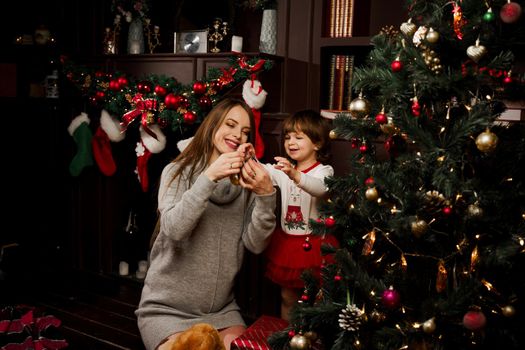 Mom and daughter decorate the christmas tree before the new year. Family traditions. Preparing for new year celebration